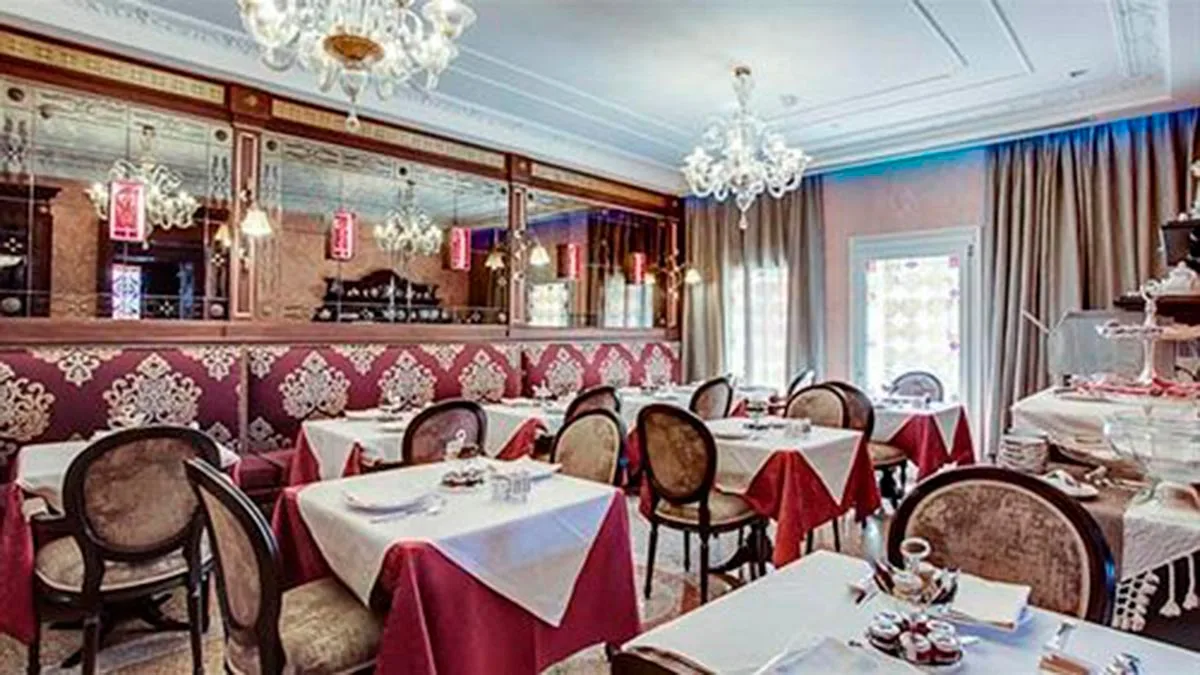 A restaurant furnished with Baroque-style tables, chairs and chandeliers